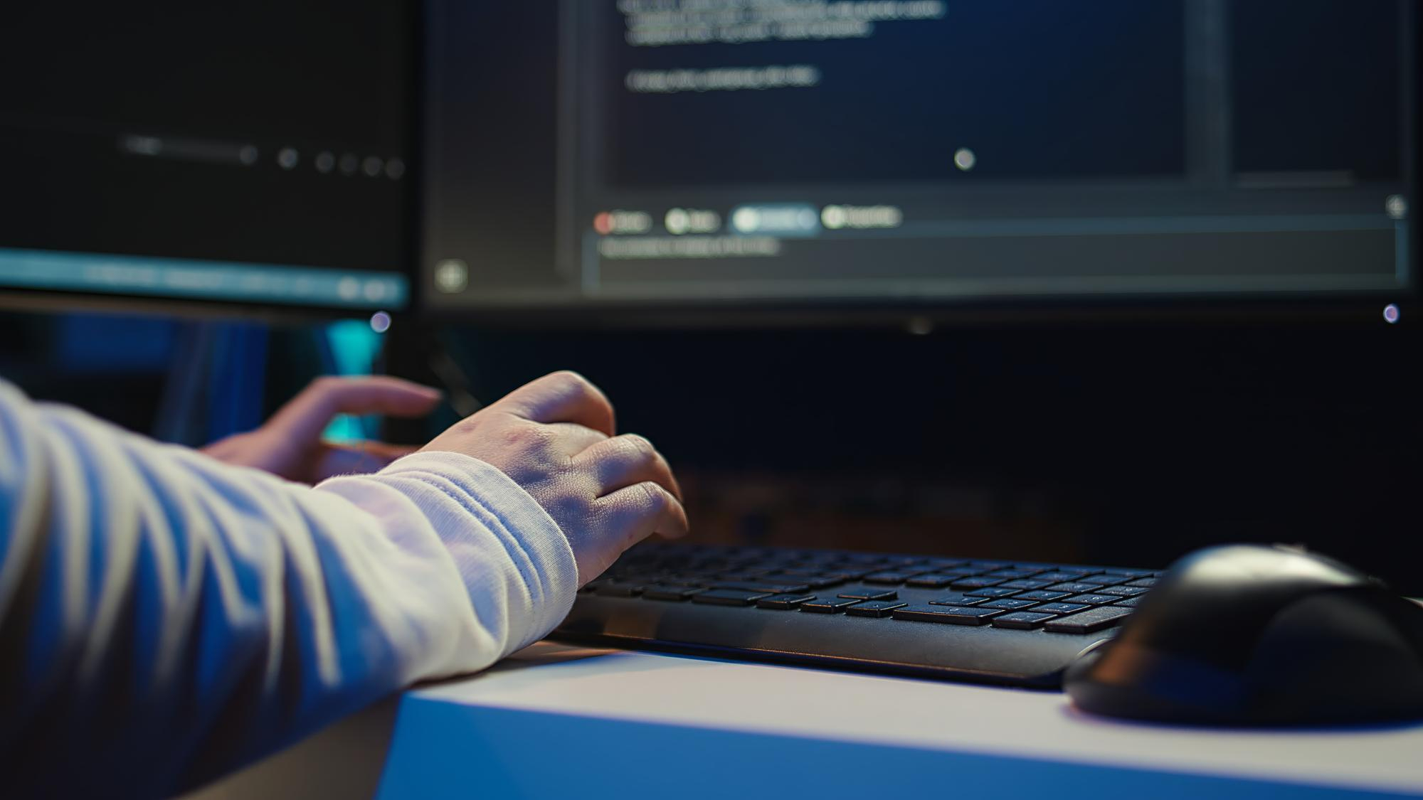 Marketopia developer typing code on a keyboard in a dimly lit office